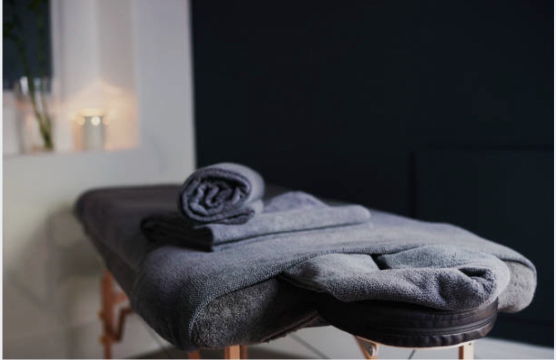 Soft draped fabric and ambient light evoking a quiet in-home massage setting